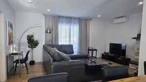 A modern living room with a sofa, TV, and dining area. - Enjoy Orleans Island at Residence Orleans with it magnificent inground pool (Sainte-Pétronille)