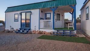 A small, single-story building with a green roof and blue accents. It features a front porch with a bench and a small table. - The Eagle's Nest: Experience Arizona Agritourism (Kingman)