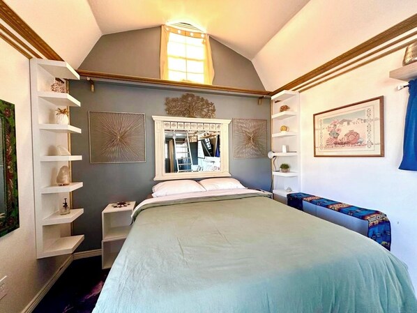Un dormitorio con cama, cómoda, espejo y estanterías.