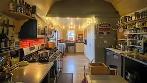 A compact kitchen with a gas stove, shelves with bottles, and a sign reading "GOOD MORNING COFFEE SHOP FRESH BREWED." - The Eagle's Nest: Experience Arizona Agritourism (Kingman)