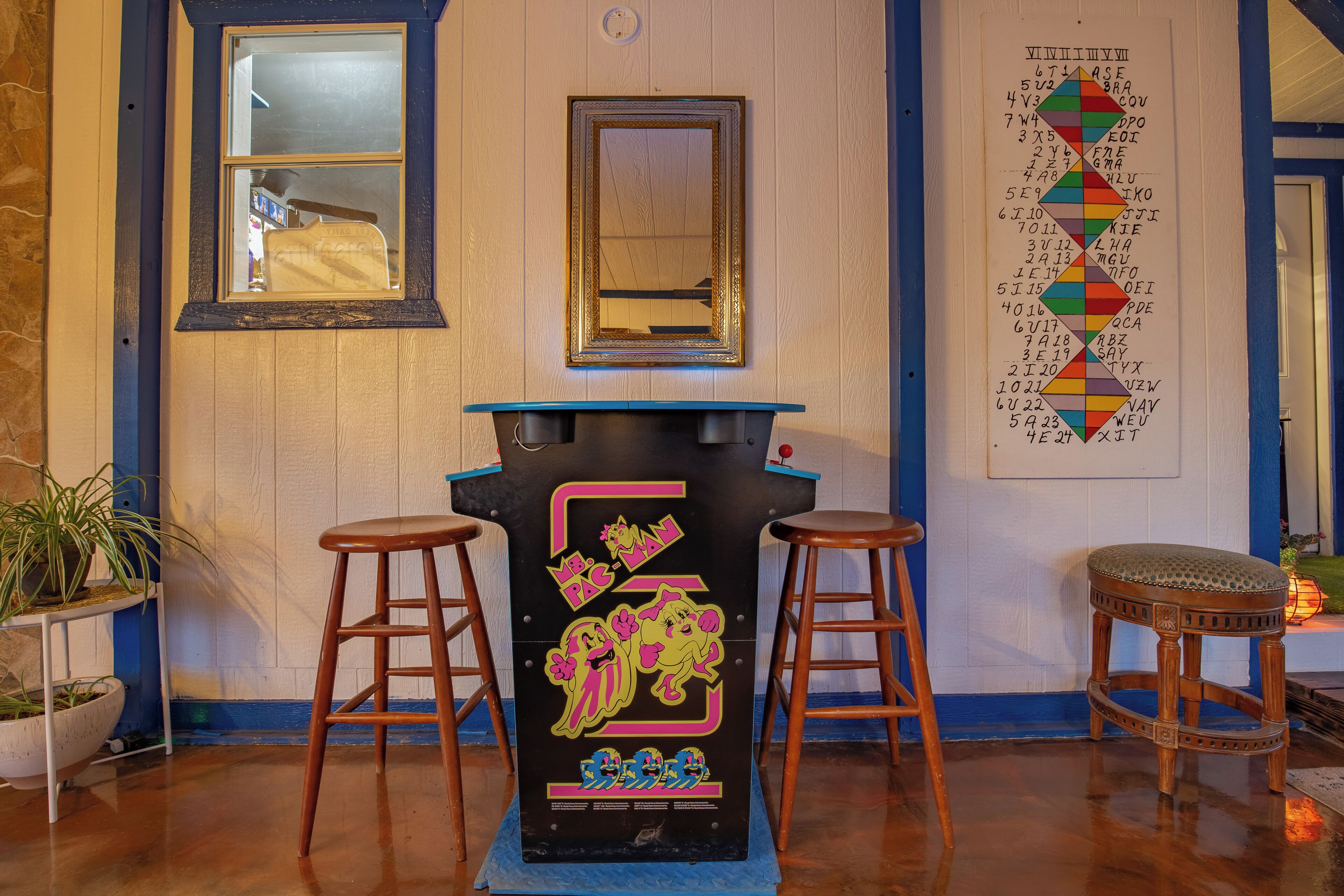 A bar area with stools, a mirror, and a wall with a colorful chart.