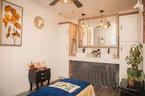 Un dormitorio con cama, cómoda, mesita de noche, espejo y ventilador de techo.