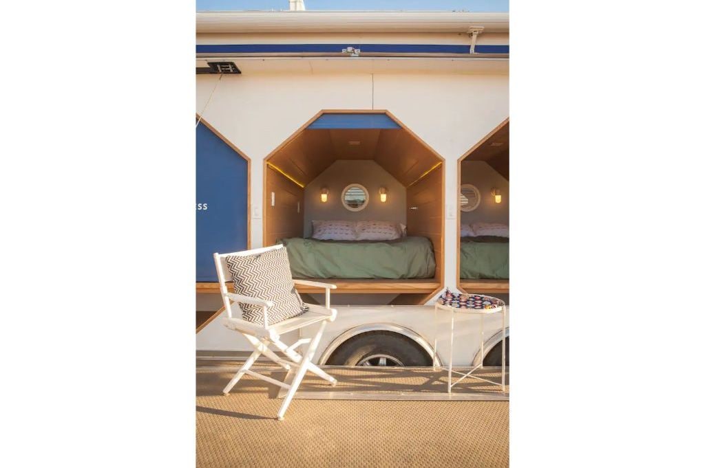 Een compacte, goed verlichte kamer met een bed, een klein tafeltje en een stoel.