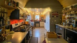 A cozy kitchen with a wooden ceiling, a stove, and shelves with bottles and jars. - The Coyote Den #3: Experience Arizona Agritourism (Kingman)
