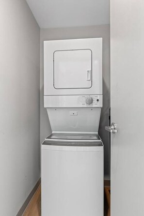 A compact, white, wall-mounted washer and dryer unit in a narrow hallway with a wooden floor. - Penthouse @ 175 LEX -Walk to Rupp Arena on Main St (Lexington)
