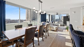 A modern living room with a dining area, large windows, and a city view. - Penthouse @ 175 LEX -Walk to Rupp Arena on Main St (Lexington)