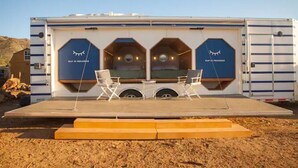 Un camping-car aménagé en scène mobile, avec deux chaises et un panneau indiquant : « PLAN EN COURS DE RÉALISATION ».