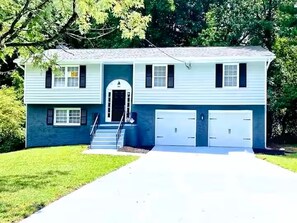 A two-story house with a front entrance, a covered porch, and a driveway leading to a garage.