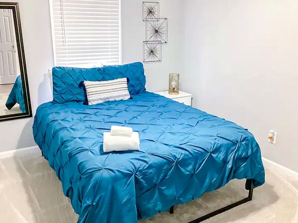 A bedroom with a bed, a nightstand, a mirror, and wall art. - ATL Lakeview Retreat - Holiday Getaway (Decatur)
