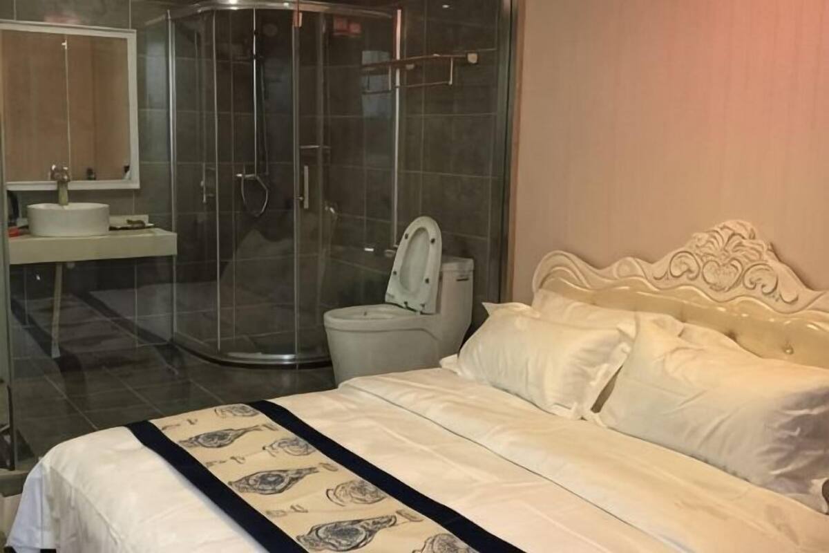 A bedroom with a bed, a shower, and a toilet.