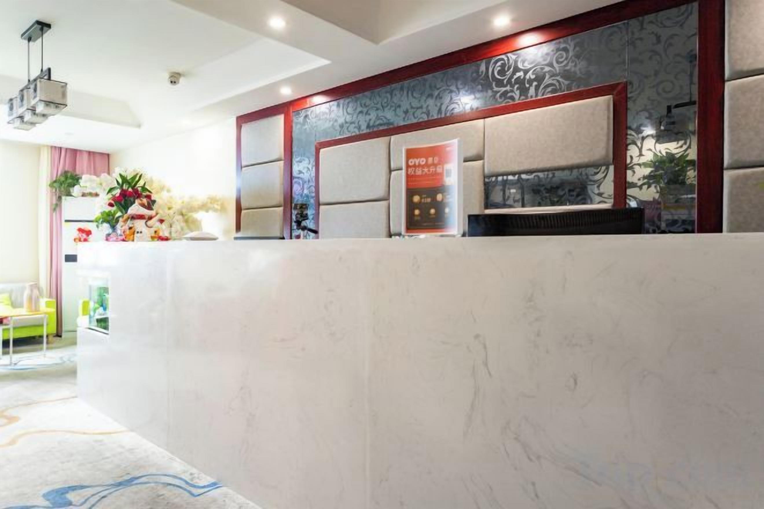 A hotel reception area with a marble counter, a reception desk, and a wall-mounted TV.