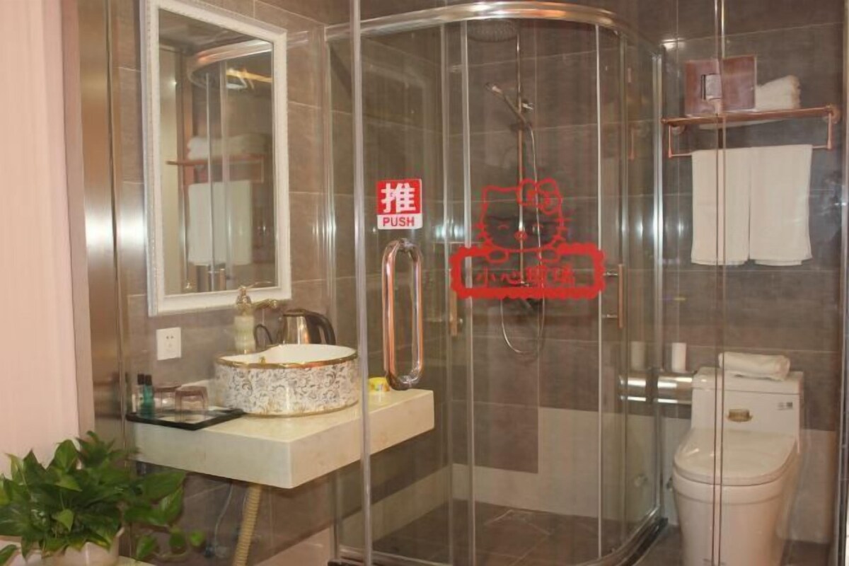 Un baño moderno con ducha envuelta en vidrio, lavamanos con un recipiente decorativo y un inodoro.