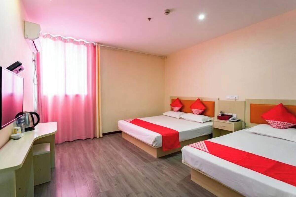 A hotel room with two beds, a desk, a mirror, and a window with curtains.