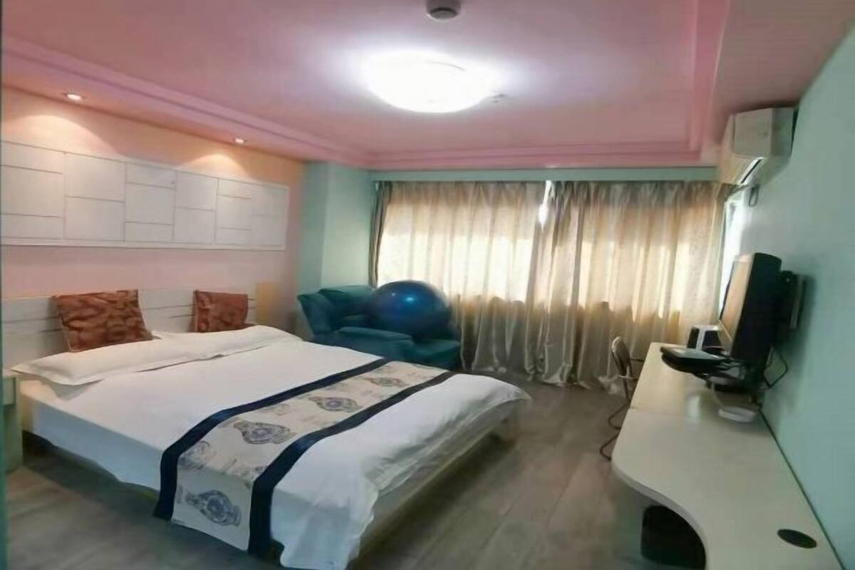 A hotel room with a bed, a desk, a chair, and a television.