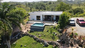 A modern house with a swimming pool, surrounded by lush greenery and hills. - splendid villa with its infinity pool offering you a view of nature (Las Terrenas)