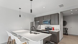 A modern kitchen with a central island, stainless steel appliances, and a minimalist design. - 175 LEX - Spacious Two Bedroom! Walkable Downtown! (Lexington)