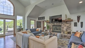 A spacious living room with a stone fireplace, comfortable seating, and large windows. - Wildflower Lotus Farm a Luxurious 5bd Home w/ Pool, Firepit and more (Gardiner)