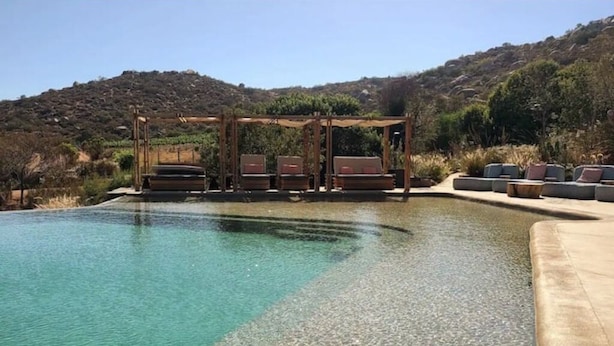 Una piscina cristalina con una pérgola y sillones de descanso.