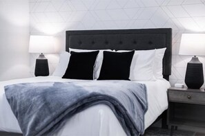 A neatly made bed with a grey blanket, two black and white pillows, and a dark headboard. There are two bedside lamps on either side of the bed. - Diamond Desert Gem: Heated Pool & Spa Oasis, 5 min from Old Town Scottsdale! (Scottsdale)