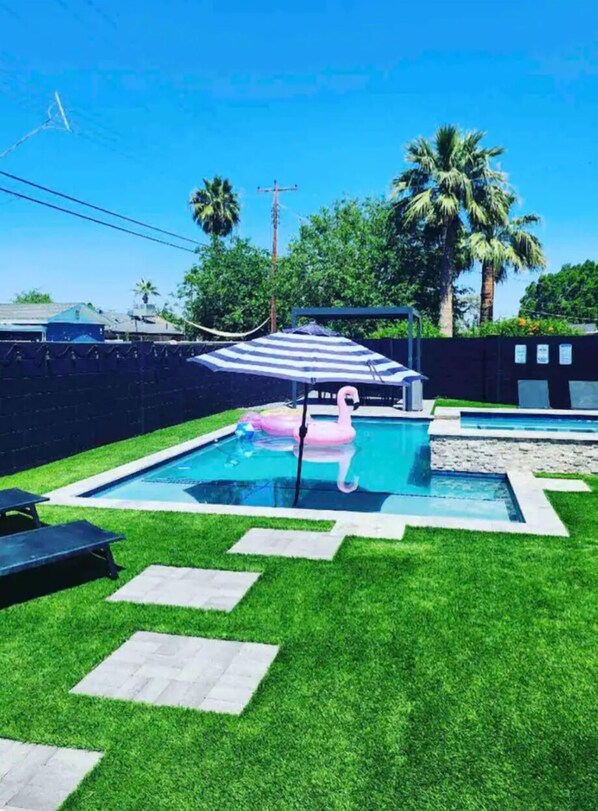 A backyard with a swimming pool, a hammock, and a flamingo float. - Diamond Desert Gem: Heated Pool & Spa Oasis, 5 min from Old Town Scottsdale! (Scottsdale)