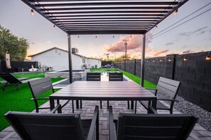 An outdoor patio with a table and chairs, a covered seating area, and a view of a building in the background. - Diamond Desert Gem: Heated Pool & Spa Oasis, 5 min from Old Town Scottsdale! (Scottsdale)