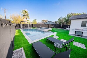 A backyard with a swimming pool, artificial grass, and outdoor furniture. - Diamond Desert Gem: Heated Pool & Spa Oasis, 5 min from Old Town Scottsdale! (Scottsdale)