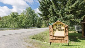 A wooden sign for Gillies Lake Cottages with a gravel road and trees in the background.