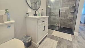 Un bagno moderno con cabina doccia in vetro, un mobile lavabo bianco e uno specchio grande.
