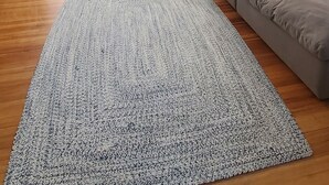 Un soggiorno moderno con un divano componibile, un tappeto decorativo e un pavimento in legno.