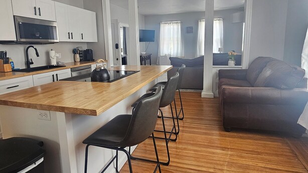 Una cucina moderna con mobili bianchi, un piano di lavoro in legno e una ventola a soffitto.