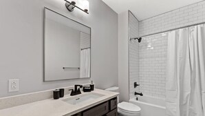 A modern bathroom with a large mirror, a sink, a toilet, and a shower area. - 175 LEX - Quiet Loft Near Rupp Arena & Restaurants (Lexington)