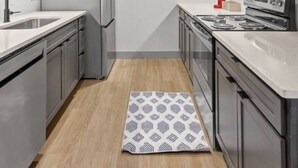A modern kitchen with grey cabinets, stainless steel appliances, and a wooden floor. - 175 LEX - Quiet Loft Near Rupp Arena & Restaurants (Lexington)
