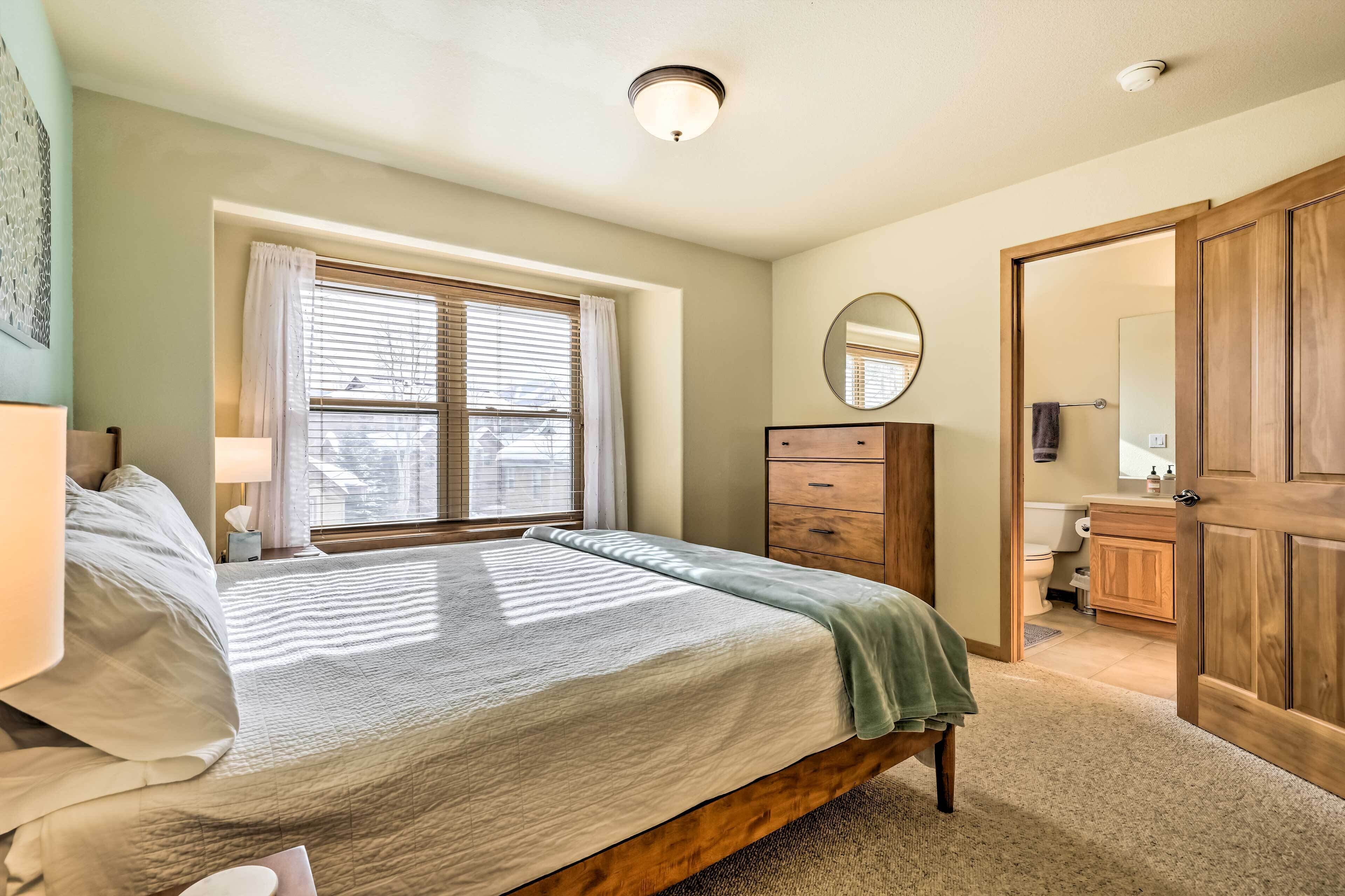 A bedroom with a bed, a dresser, a mirror, and a window with blinds.