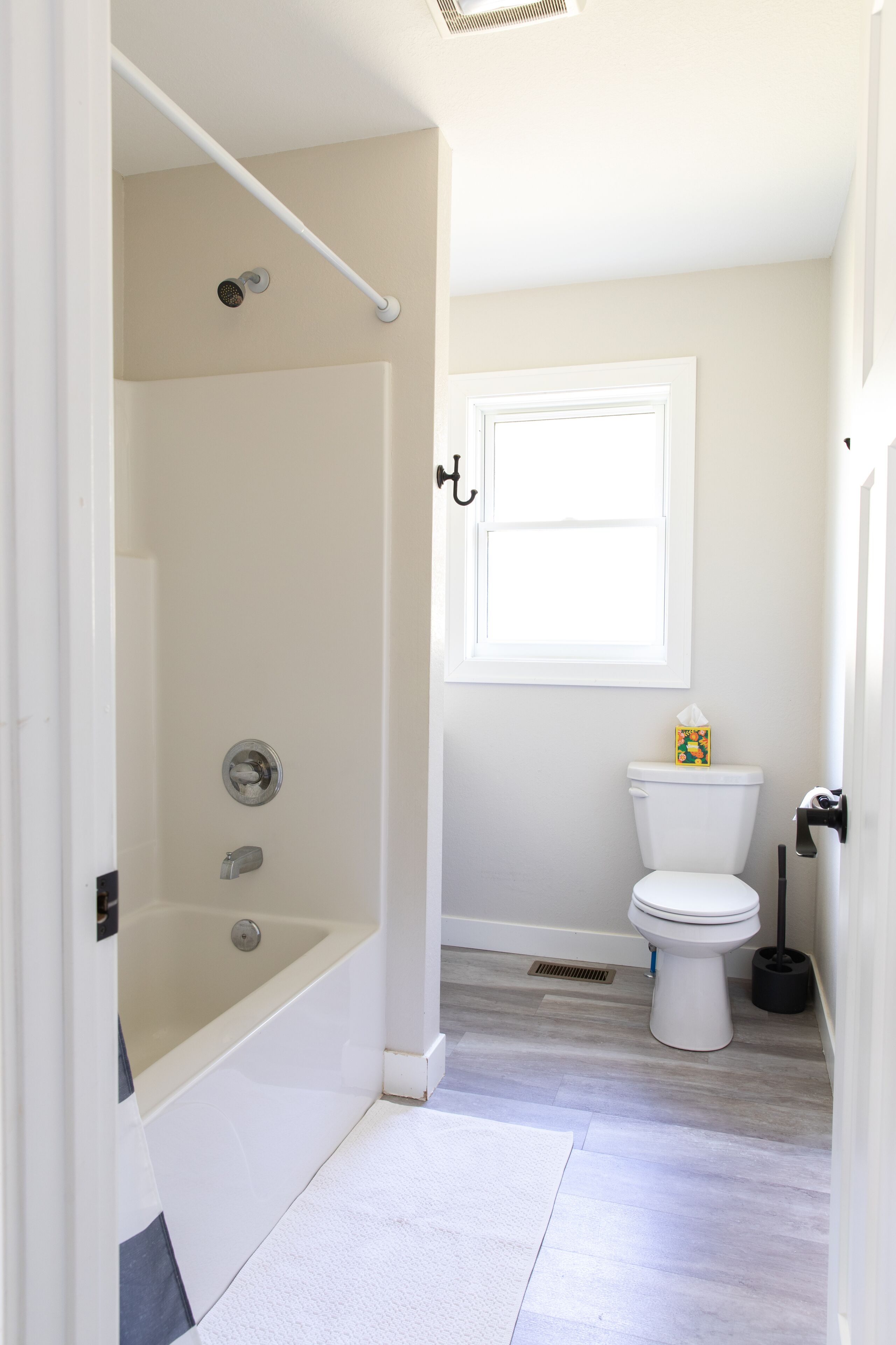 A bathroom with a bathtub, toilet, and a window.