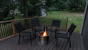 A deck with a metal fire pit surrounded by four chairs. - House near Trout Run Trail w/EV charger (Decorah)