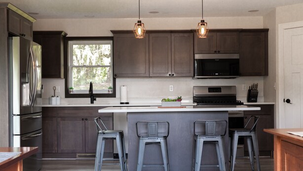 A modern kitchen with dark cabinets, stainless steel appliances, and a central island with bar stools. - House near Trout Run Trail w/EV charger (Decorah)