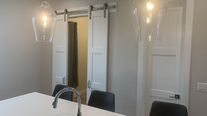 Un espace repas moderne avec une table blanche, des chaises noires et un robinet chromé.