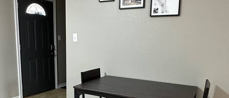 Un área de comedor con una mesa y sillas de madera oscura, además de un banco y una alfombra.
