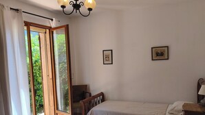 Une chambre avec deux lits, un lustre, une fenêtre avec des rideaux et une porte donnant sur l’extérieur.