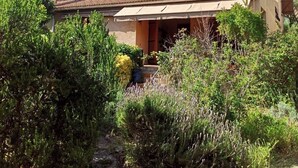 Une maison à deux étages, avec un toit recouvert de tuiles, des antennes paraboliques et un porche abrité.