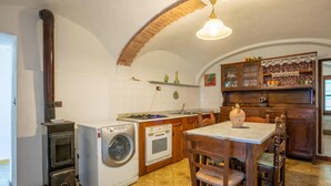 A compact kitchen with a washing machine, oven, and a dining area with a table and chairs. - Pet friendly apartment (Vignale Monferrato)
