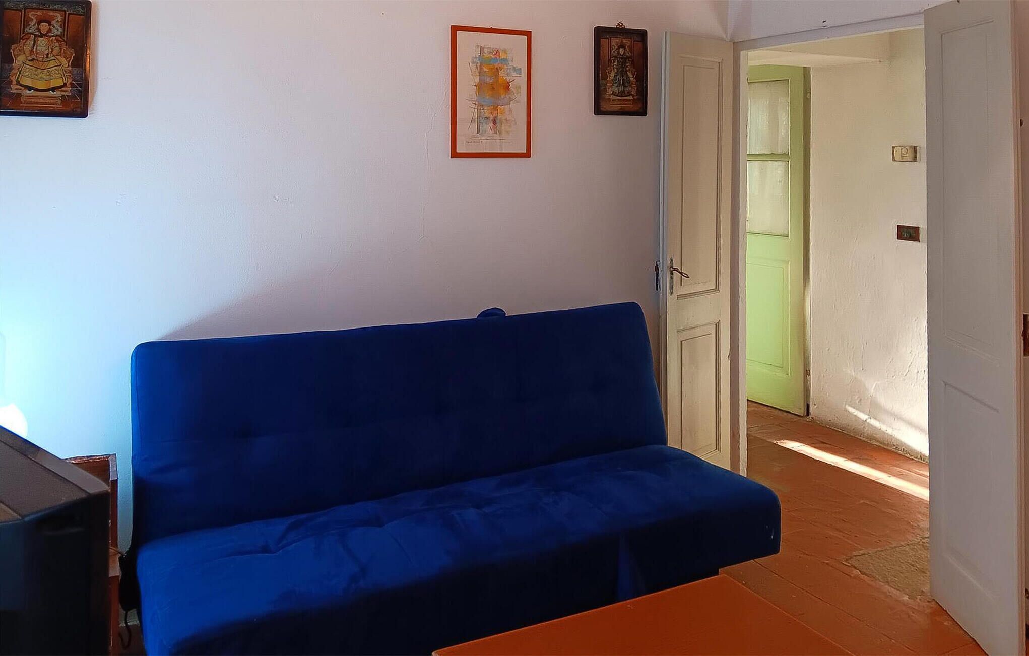 A room with a blue sofa, a small table, and a door leading to another room.