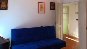A room with a blue sofa, a small table, and a door leading to another room. - Pet friendly apartment (Vignale Monferrato)