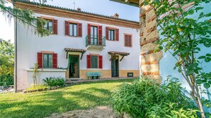 A two-story house with red shutters, a balcony, and a small garden area. - Pet friendly apartment (Vignale Monferrato)