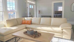 Un soggiorno con un divano angolare beige, un tavolino in legno e un tappeto a motivi.