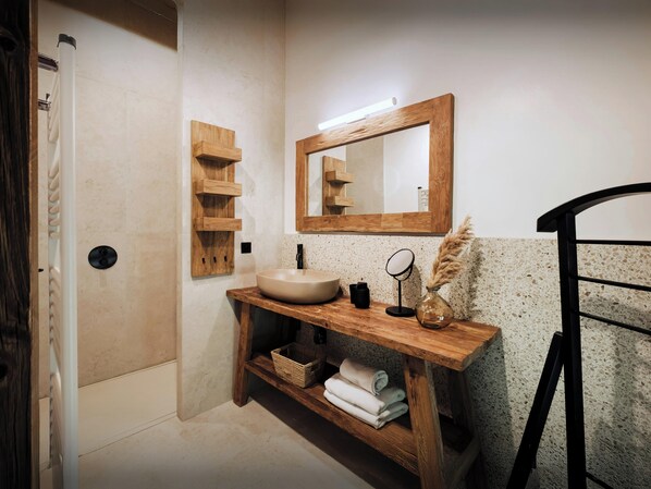 A bathroom with a wooden vanity, a large mirror, a sink, and a towel rack.
