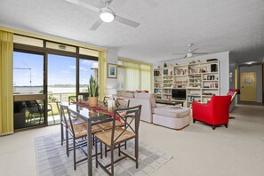 A spacious living room with a dining area, large windows, and a bookshelf. - Lovely 3 bedrooms condo with a stunning view (Ballina)