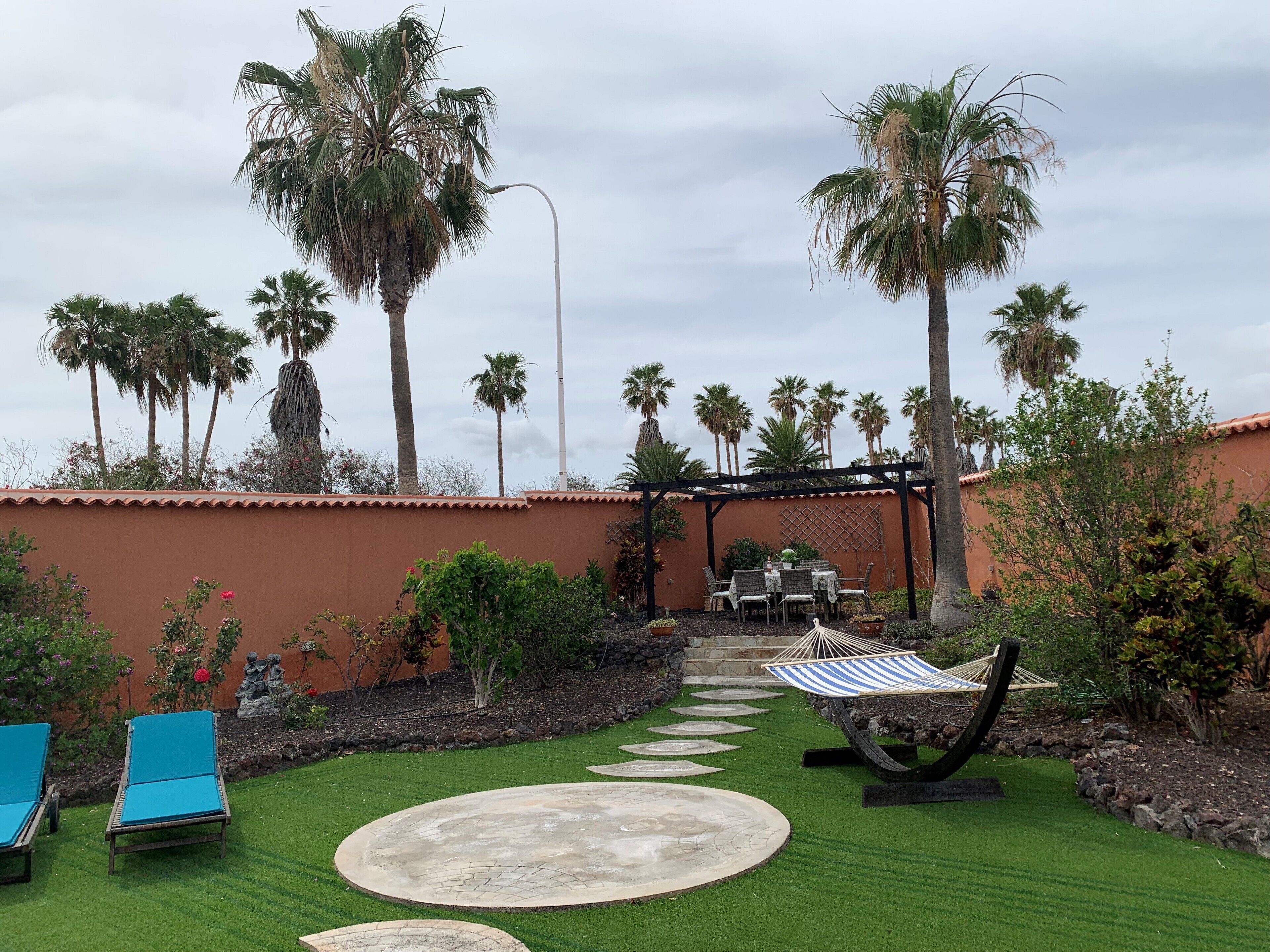 A patio area with a pergola, outdoor seating, and palm trees.