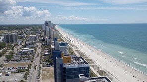 Un paisaje urbano costero con playa, edificios altos y cielo despejado.