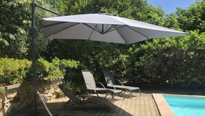 Un espace aménagé au bord de la piscine, avec des chaises longues et un parasol.